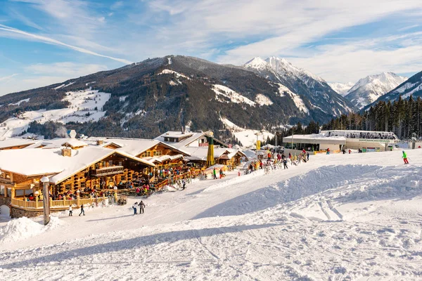 Ristorante alpino pieno di sciatori, snowboarder nelle giornate di sole. Sullo sfondo stazione sciistica Hochwurzen gondola, montagne innevate. Austria — Foto Stock