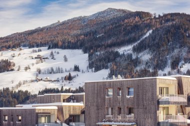 Kayak bölgesi Schladming Dachstein, Styria, Avusturya, Avrupa 'da karla kaplı çatıları ve arka planda dağları olan yeni, ahşap dağ evleri