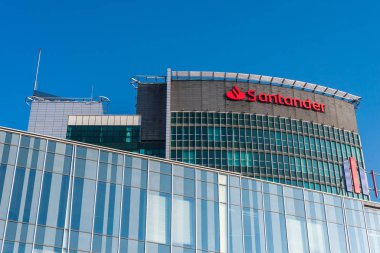 Santander Bank logosu, Eski Kent ve Poznan Uluslararası Fuarlar semtindeki Poznan Finans Merkezi 'nin merkezindeki yüksek sınıf ofis binasının tepesinde yer alıyor. Mavi gökyüzü, boşluğu kopyala.
