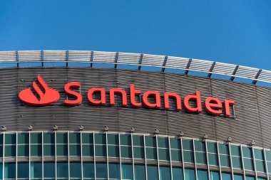 Santander Bank logosu, Eski Kent ve Poznan Uluslararası Fuarlar semtindeki Poznan Finans Merkezi 'nin merkezindeki yüksek sınıf ofis binasının tepesinde yer alıyor. Mavi gökyüzü, boşluğu kopyala.