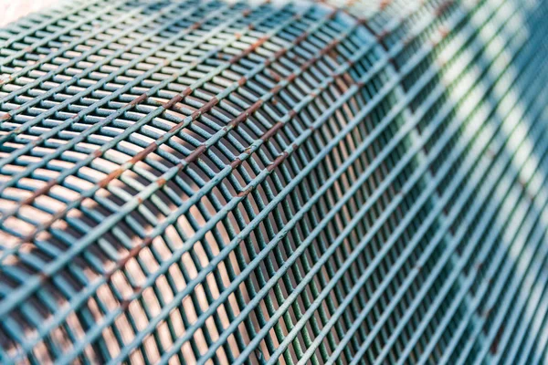 Close-up of a bench made of metal rods. Abstract background with selective focus. Clear lines and squares.