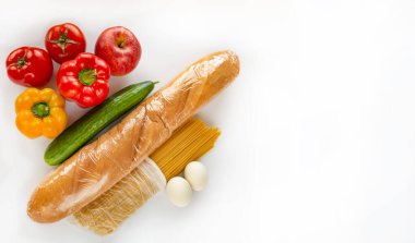 Beyaz arka planda bir market seti var. Set makarna, ekmek ve sebzeleri içeriyor. Ürünlerin koronovirüs salgını sırasında bağışlanması amaçlanıyor..