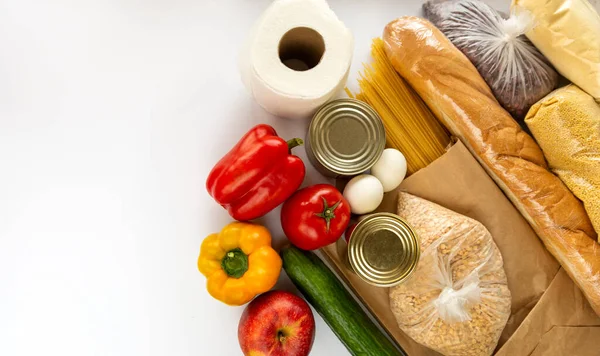 Products and essentials for a donation are placed on a white background. The set includes dry foods, bread, fruits and vegetables. Coronovirus.