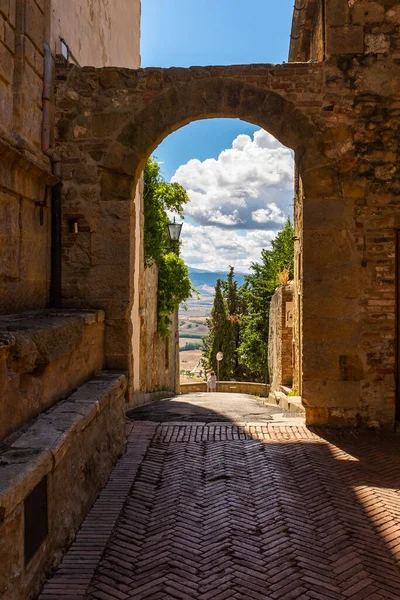 Mirando a través de un arco en una calle lateral hacia la hermosa e impresionante campiña toscana desde la ciudad de Pienza, Italia —  Fotos de Stock