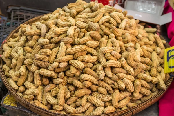 A large bowl of peanuts still in their husks at a street market in Thailand — Stock Photo, Image