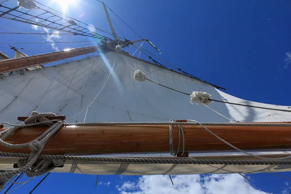 Вид с низкого угла на высокий корабль, плывущий против ярко-синего неба, поднятого с палубы лодки — стоковое фото