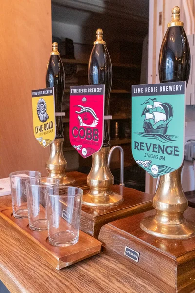 Lyme Regis, Dorset, Engeland, februari, 24, 2019: bierpompen in de brouwerij Lyme Regis, met lege sampler glazen op de voorgrond — Stockfoto