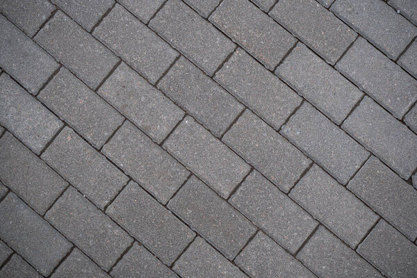 Background image of the surface of the sidewalk. Wallpaper. Substrate for text. Detailed texture of a pedestrian walkway with paving tiles. Paving slabs in the exterior. Top view.