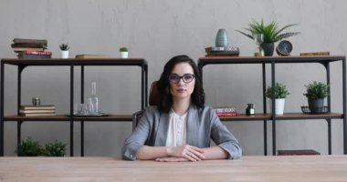 Takım elbiseli ve gözlüklü kız büroda oturuyor.