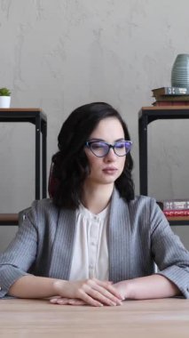 Takım elbiseli ve gözlüklü kız büroda oturuyor.