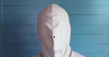 Beyaz lateks maskeli adam çok renkli gözlük takıyor.