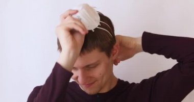 Beyaz arka plandaki adam yanlışlıkla yüzüne antiviral bir maske takıyor.