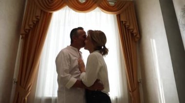Erkek ve kadın arka planda öpüşürler.