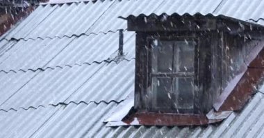 Eski ahşap bir evin arka planında şiddetli kar yağışı var.