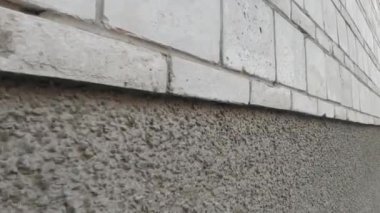 Evin gri taş duvarı boyunca sürüyordu.