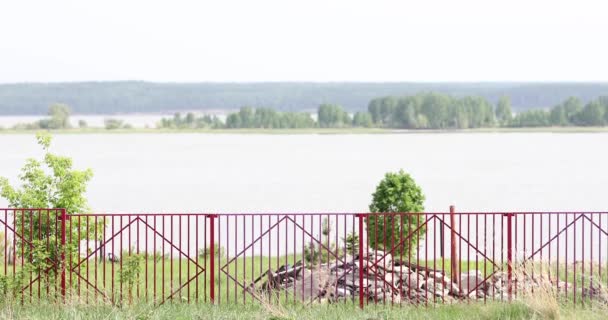 Zicht Door Een Rood Hek Van Een Bosgordel Een Meer — Stockvideo