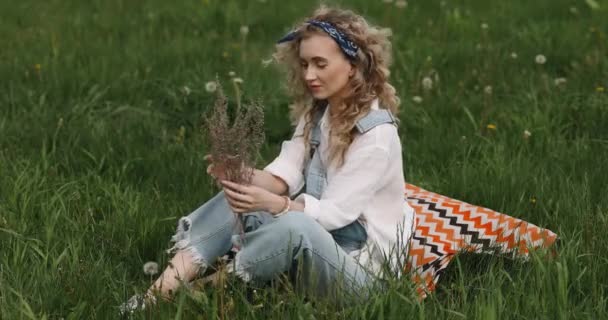 Dziewczyna Kręconymi Włosami Siedzi Trawie Kwiatami Rękach — Wideo stockowe