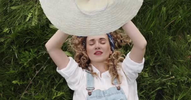 Dívka Kudrnatými Vlasy Leží Zelené Trávě Pokrývá Její Tvář Kloboukem — Stock video