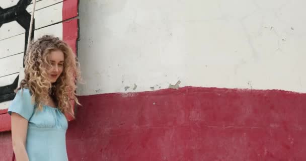Dívka Kudrnatými Vlasy Modré Šaty Chodí Pozadí Červené Budovy — Stock video