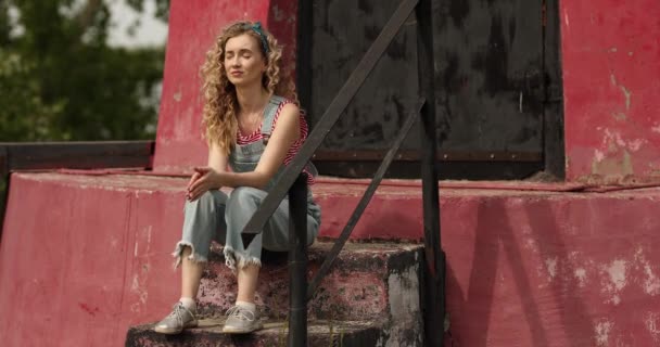 Girl Curly Hair Overalls Sits Steps Nature — Stock Video