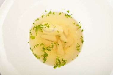 Yumurta ve etli çorba, büyük beyaz bir tabakta, beyaz arka planda.