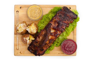 Kızarmış et, otlar, soslar, patatesler, tahtanın üzerinde.