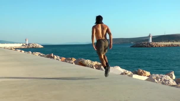 Ο άνθρωπος κάνει αθλητική προπόνηση κοντά στη θάλασσα για την τακτοποίηση και υγιή ζωή — Αρχείο Βίντεο