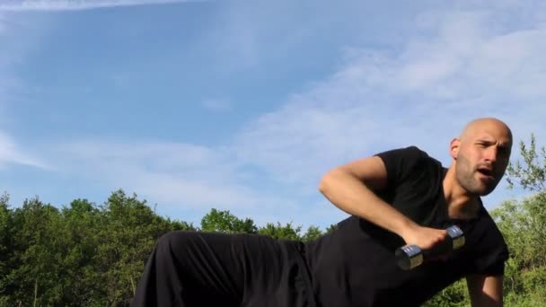 自然の中の草の上にダンベルを持つ男トレーニング — ストック動画