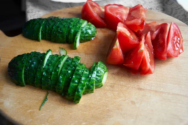 Taze kesilmiş sebzeler. Salatalık ve domatesler ev mutfağındaki tahtada yatıyor. Doğal bakış. Görüntü..