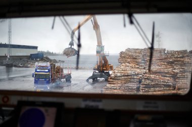 Husum / İsveç - 7.05.2019: Husum limanında kereste kargosunun boşaltılması. Kıyı vinciyle kamyona kereste yüklüyorum. Bulanık. 