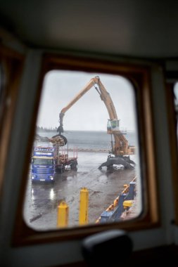 Husum / Sweden - 7.05.2019:   Discharging of timber cargo in port Husum. Loading timber on truck by shore crane. Blur.  clipart
