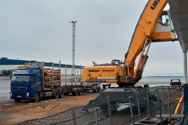 Husum / İsveç - 7.05.2019: Husum limanında kereste kargosunun boşaltılması. Kıyı vinciyle kamyona kereste yüklüyorum. Bulanık. 