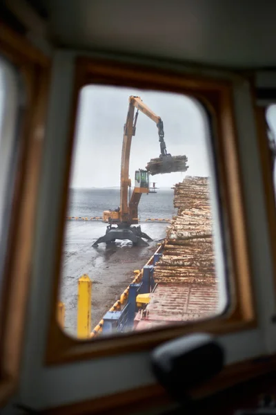 Husum / İsveç - 7.05.2019: Husum limanında kereste kargosunun boşaltılması. Kıyı vinciyle kamyona kereste yüklüyorum. Bulanık. 