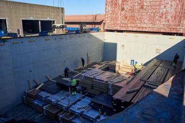 Vejle / Danimarka - 05.16.2019: kargo gemisinin ambarından çelik ürünlerin boşaltılması. Kargo Finlandiya 'dan Danimarka' ya gönderildi. Yaşlı limanlar kargo bölümünde çalışıyor.