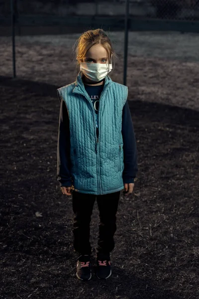 Maskeli bir kızın dramatik portresi. Coratntin kullanırken üzgün bir kız sokakta yürüyor. Batan güneşin arka planındaki kız.