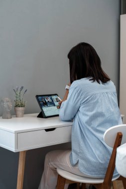 Bir güzellik uzmanı ofisinde oturuyor ve koronavirüs karantinası sırasında tablete bakıyor. Kendini soyutlama. Arkadan bak.