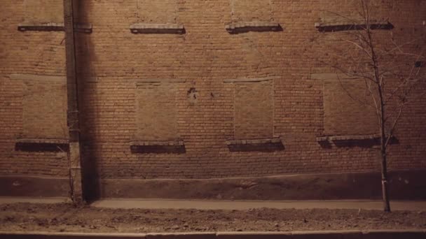 A lone man stands outside at night during quarantine. A man is wearing a blue medical mask. background of a brick wall. — Stock Video