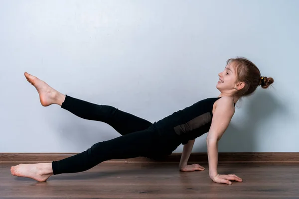 Açık tenli, sarışın bir kız karantina sırasında evde spor yapıyor. Siyah eğitim üniformalı atletik kız. Spor egzersizleri evde..