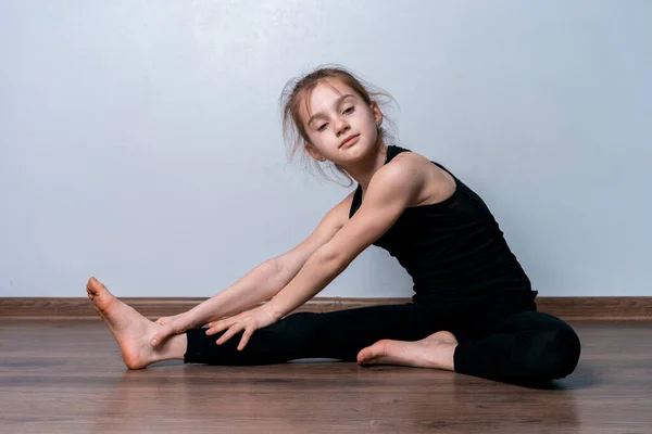 Açık tenli, sarışın bir kız karantina sırasında evde spor yapıyor. Siyah eğitim üniformalı atletik kız. Spor egzersizleri evde..