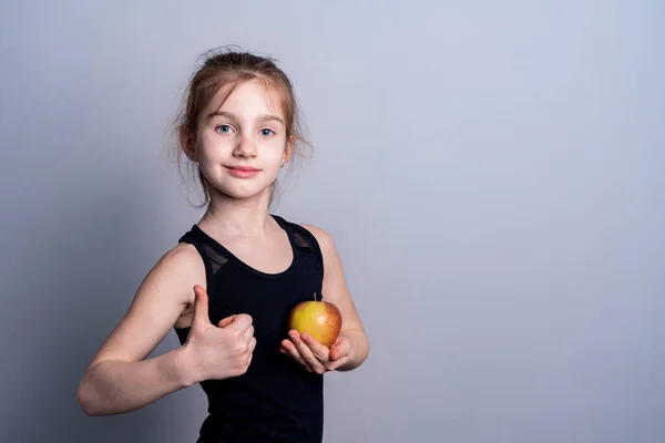 stock image A white-skinned girl in a black sweatshirt holds an apple in her hand. The benefits of fruit. Healthy eating Place for text.