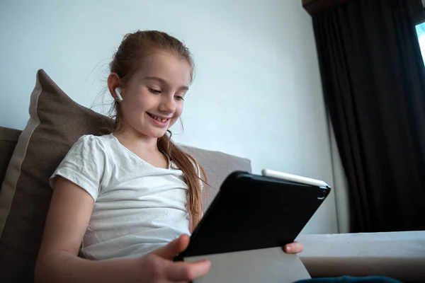 Kids home Quarantine. The child uses the tablet for self-education during quarantine. The girl is studying online. A child is looking for information on the Internet.