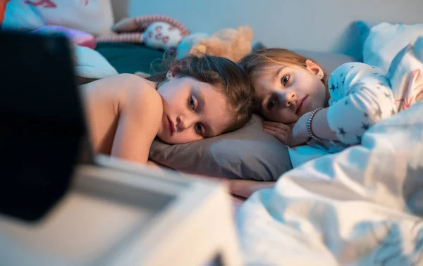 Két Kislány Nővér Feküdt Este Ágyukban Egy Rajzfilmet Néztek Tablettákon — Stock Fotó