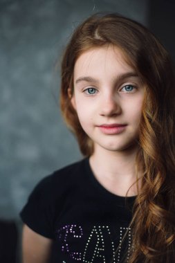 Beyaz tenli, kıvırcık saçlı bir kızın portresi. Kız kameraya bakıyor. Genç bir kızın hassas ve şehvetli portresi. Yakın plan.