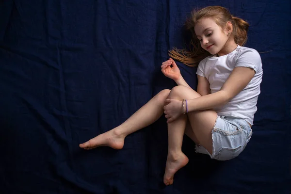 一个白皙的女孩躺在蓝色的背景上 摆出一副漂亮的姿势 体育女孩 后续行动 图库图片