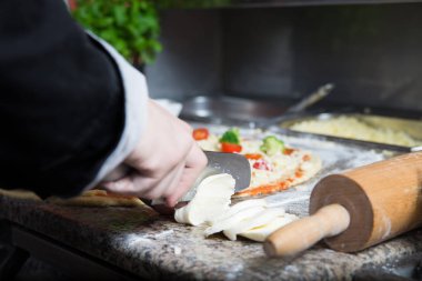 Adam mozarella için el yapımı pizza katacak peynir kesti.