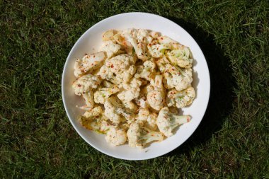 Bir tabak çiğ karnabahar ve biber serpiştirilmiş.