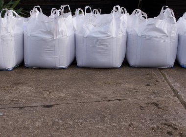 Ön planda beton olan beyaz plastik kum torbaları.