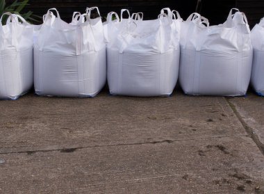 Row of white plastic sand bags with concrete in foreground clipart