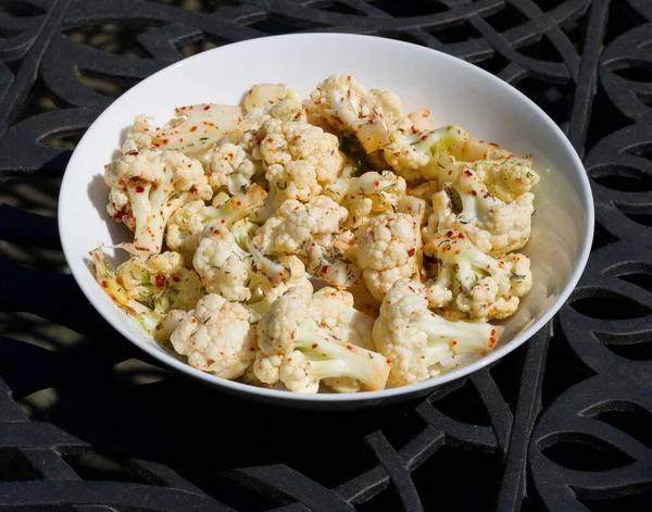 A bowl of raw cauliflower in round dish sprinkled with chilli — Stock Photo, Image