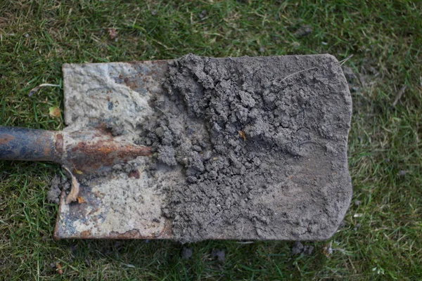 Грязная ржавая металлическая лопата, лежащая на высокой лужайке — стоковое фото